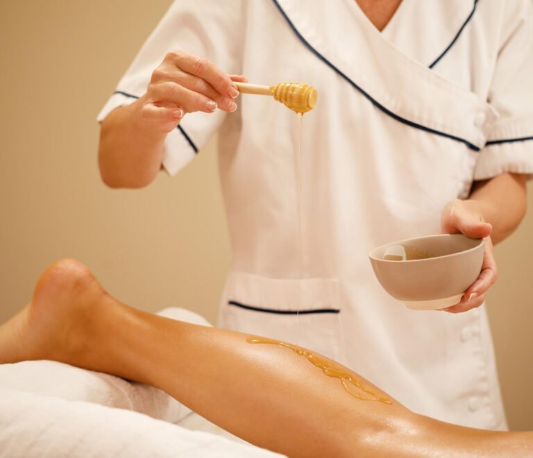 unrecognizable-therapist-pouring-honey-while-massaging-woman-s-leg-spa-salon